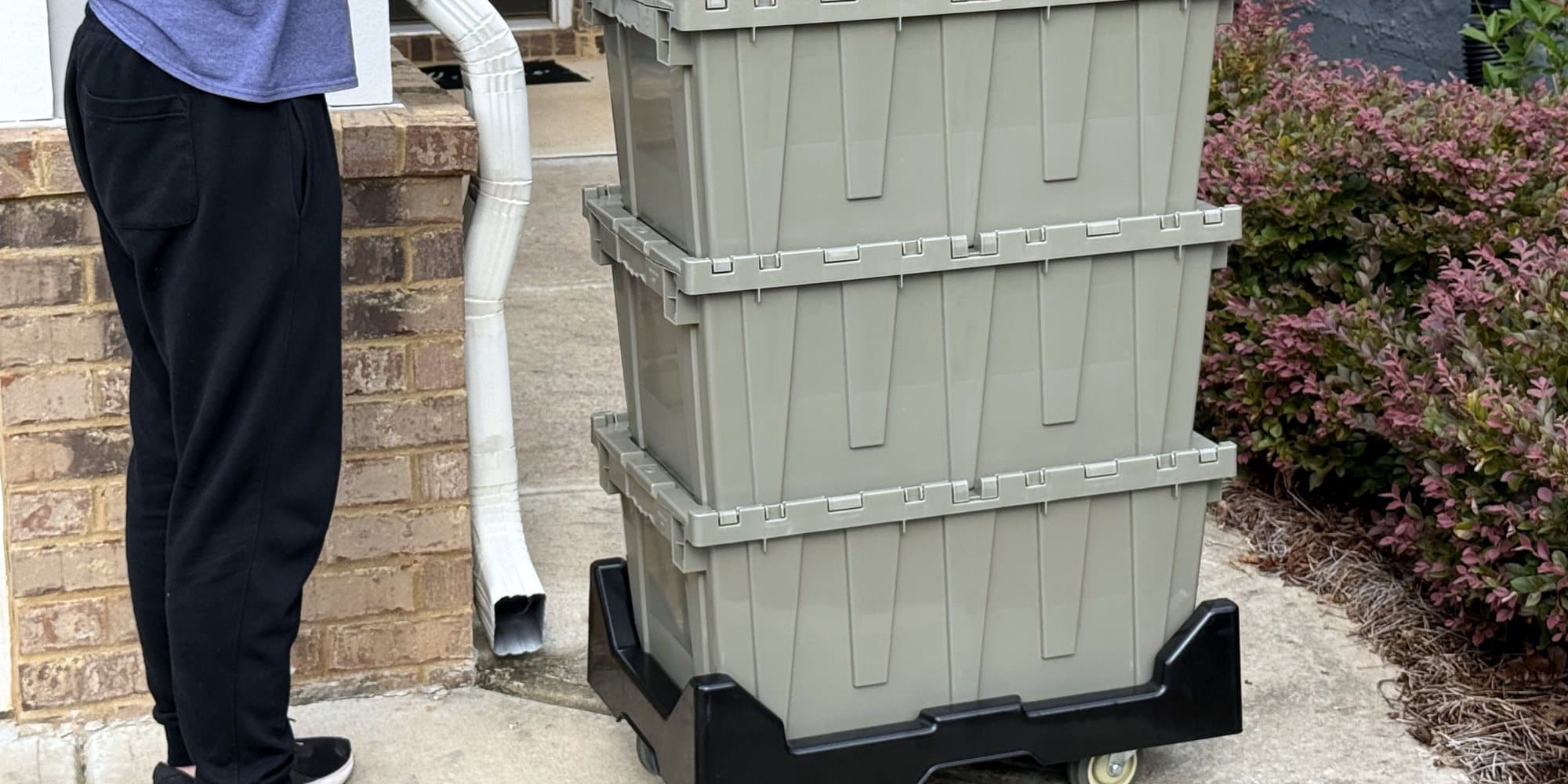 Three loaded Cherokee Crate totes on a dolly being wheeled up a walkway