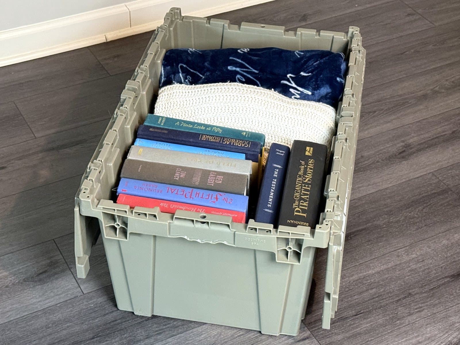 An open Cherokee Crate tote packed with books and folded blankets, lid folded out to the sides